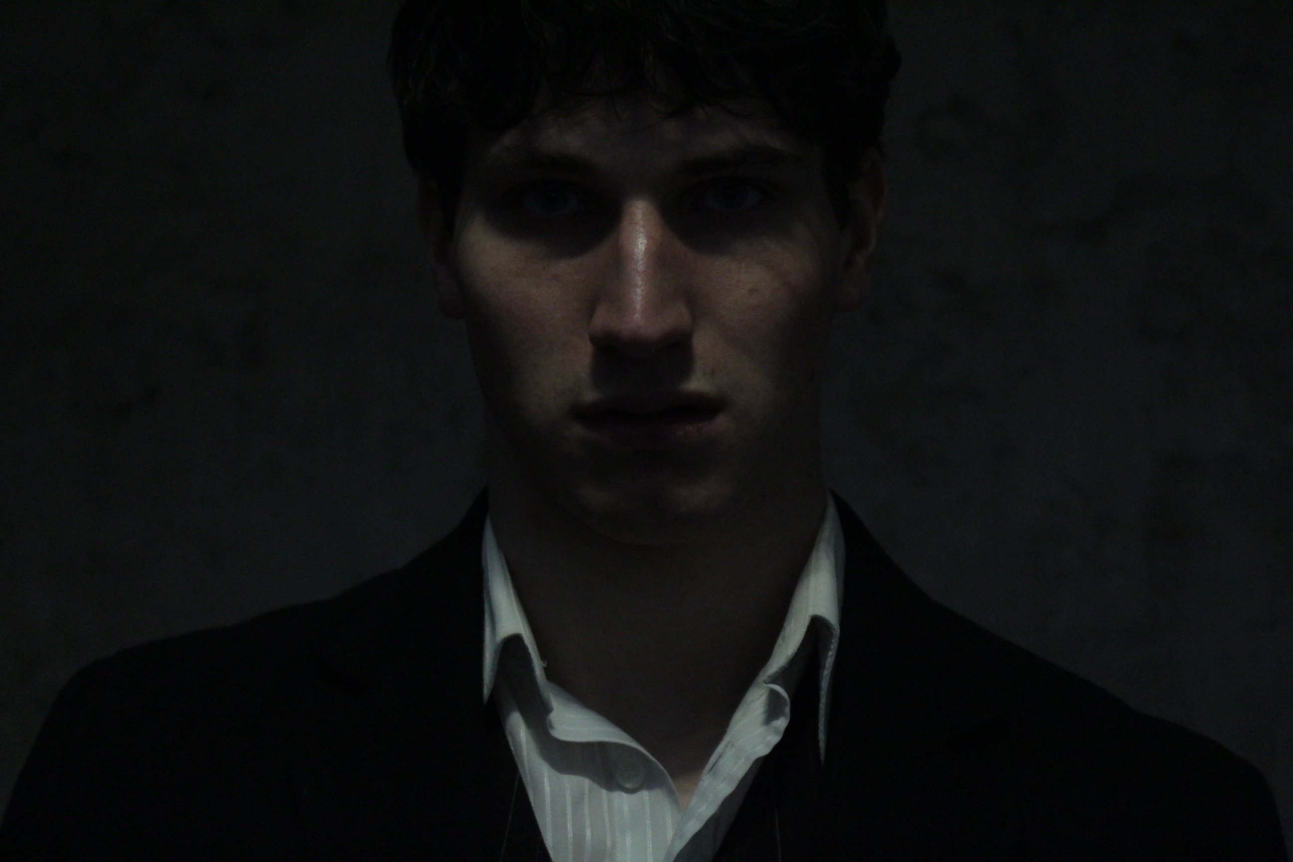 Close promotional portrait against a bare wall.