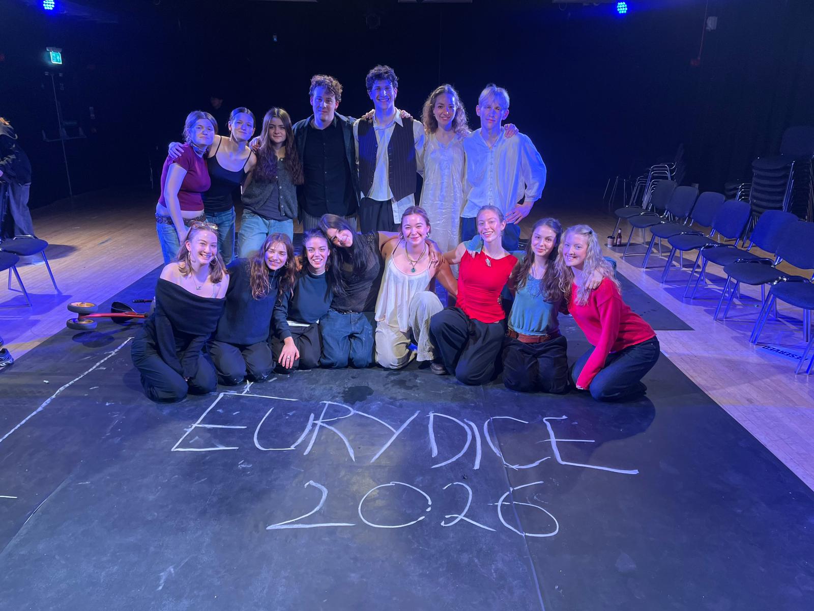 The cast and crew gathered on stage behind chalk lettering reading Eurydice 2026.