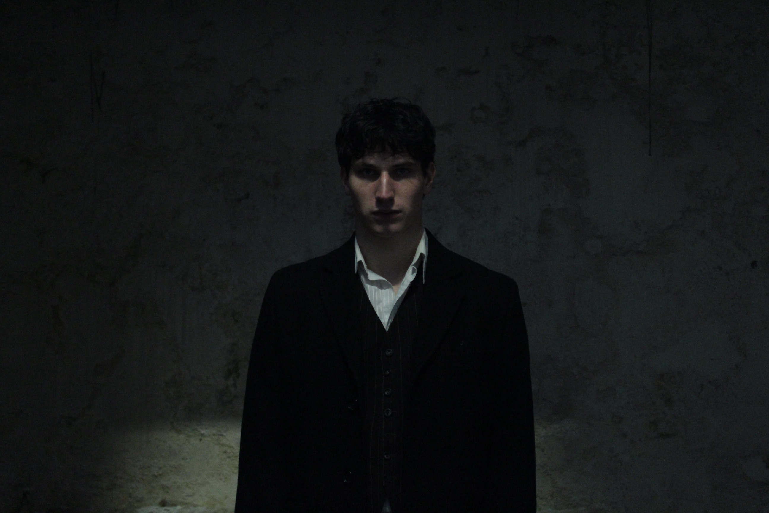 Promotional portrait of the Lord of the Underworld in a long dark coat.